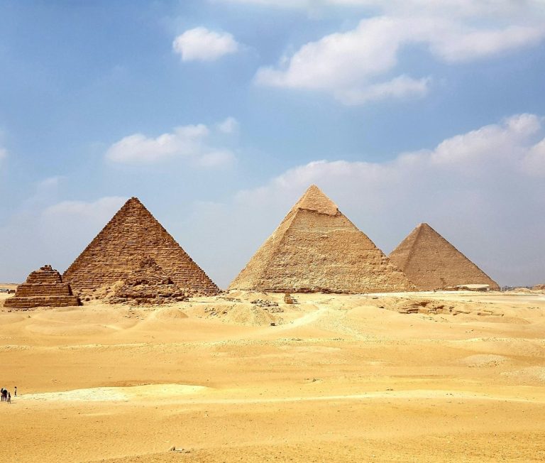 Egypte Trois grandes pyramides de Gizeh sur un paysage désertique sous un ciel bleu.