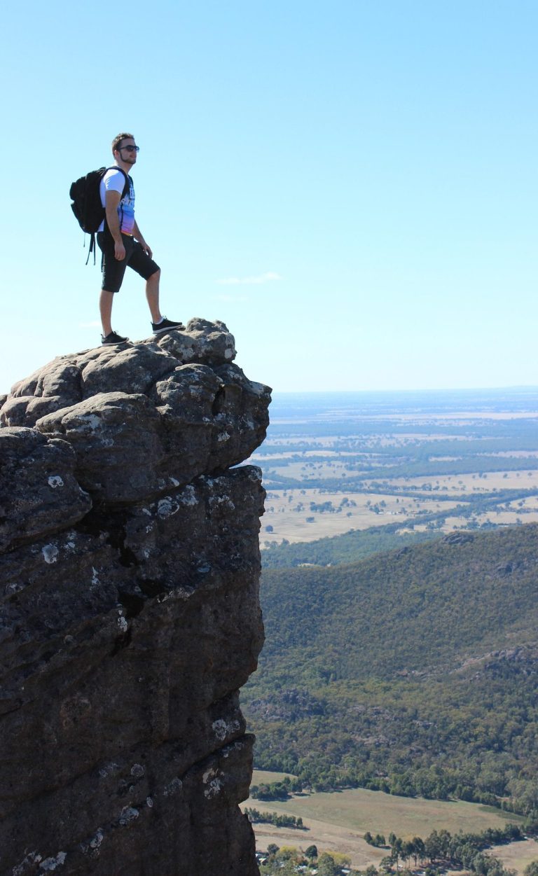 Newsletter Homme debout sur un rocher au sommet d'une colline, vue panoramique sur la vallée.